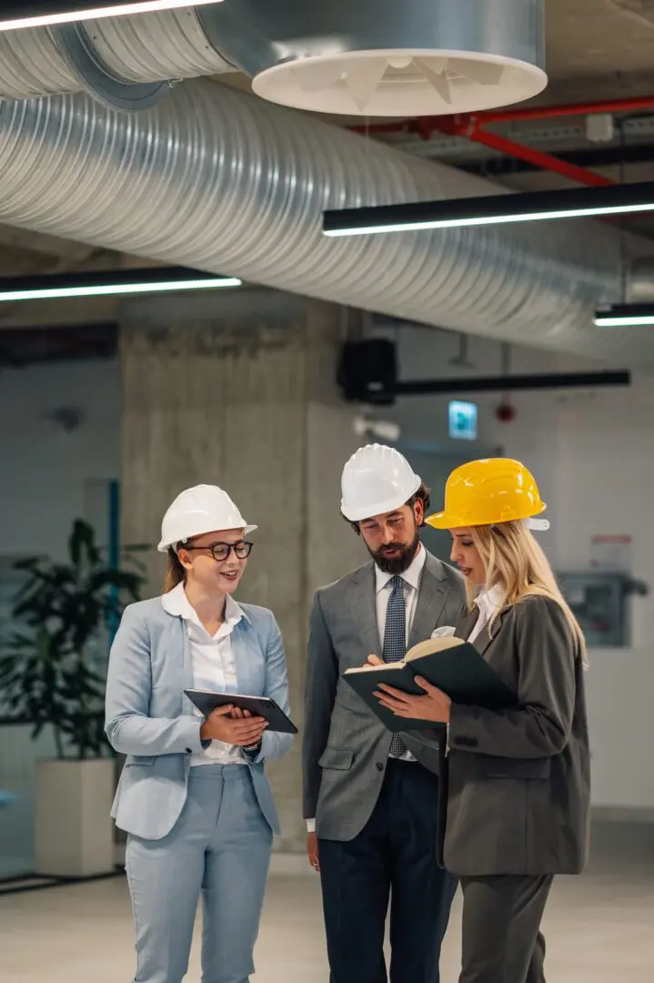 Three professionals discussing plans in hard hats.